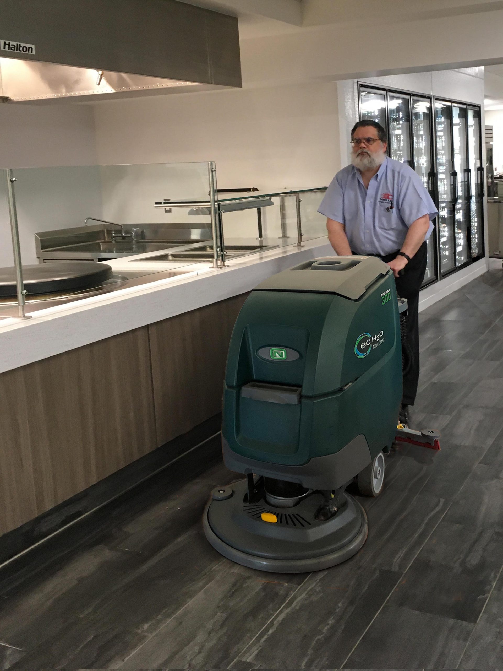 Man pushing floor cleaner through office hallway