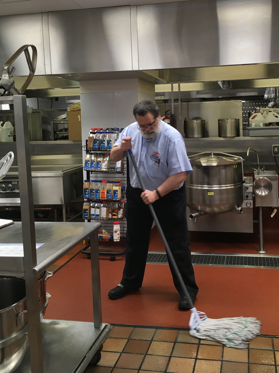 man mopping floor in a commercial kitchen
